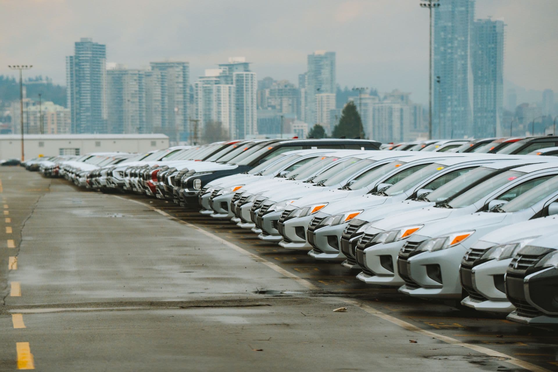 Rij geparkeerde personenauto's met een skyline op de achtergrond