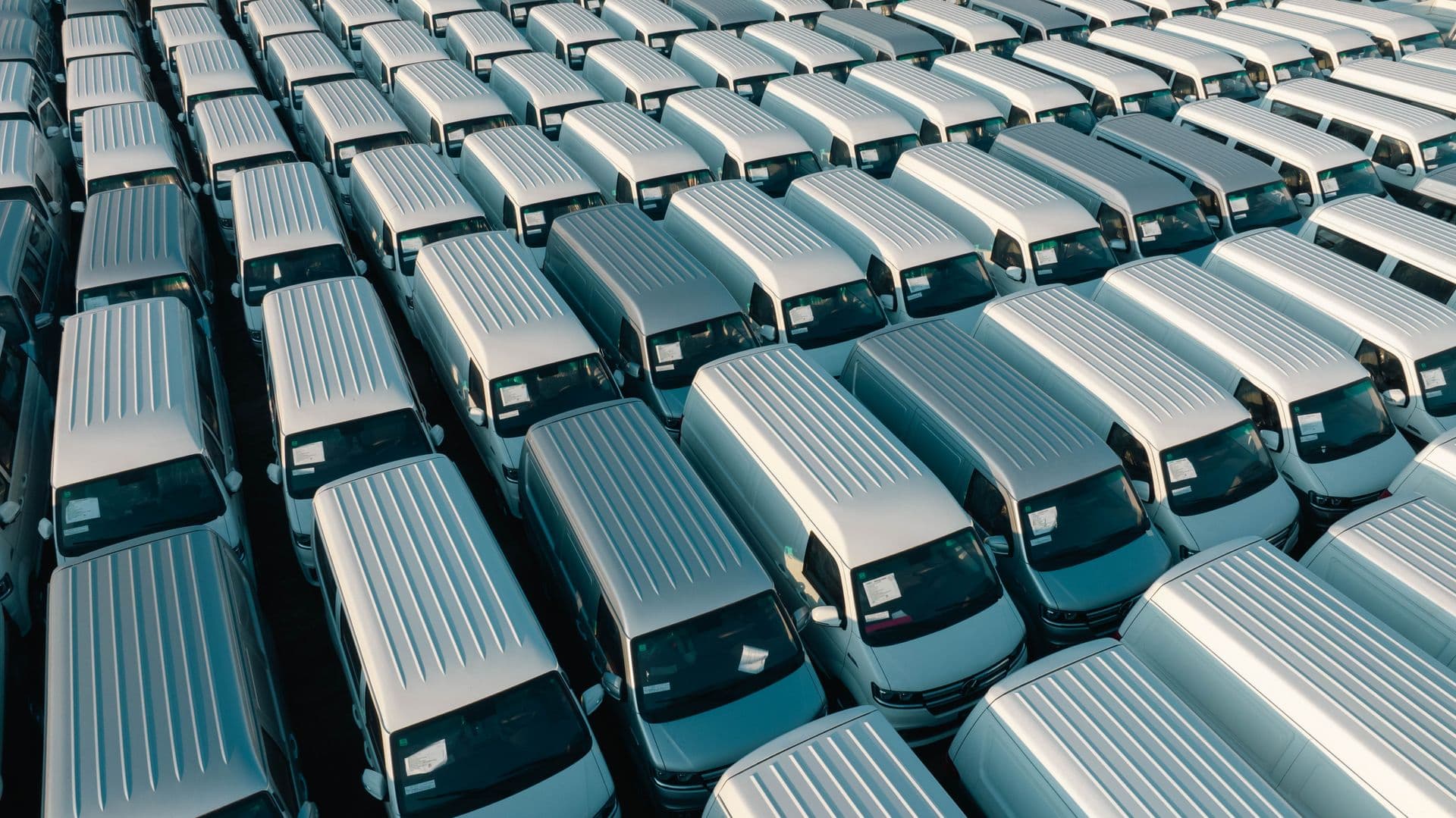 Bedrijfsbussen in strakke rijen op een parkeerterrein, van bovenaf gezien